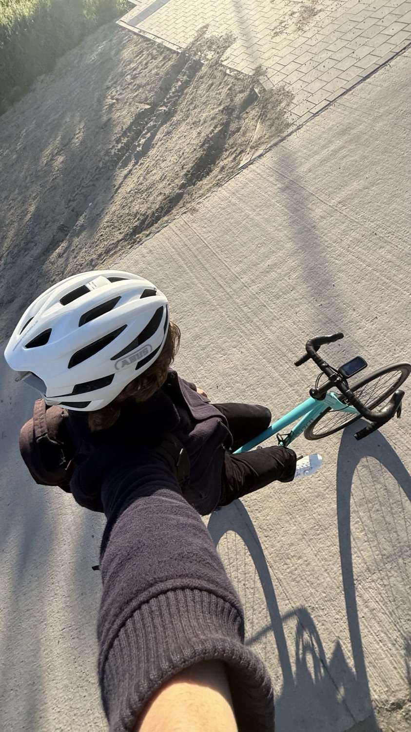 A top-down selfie in a white helmet, shadow of the bike on the road