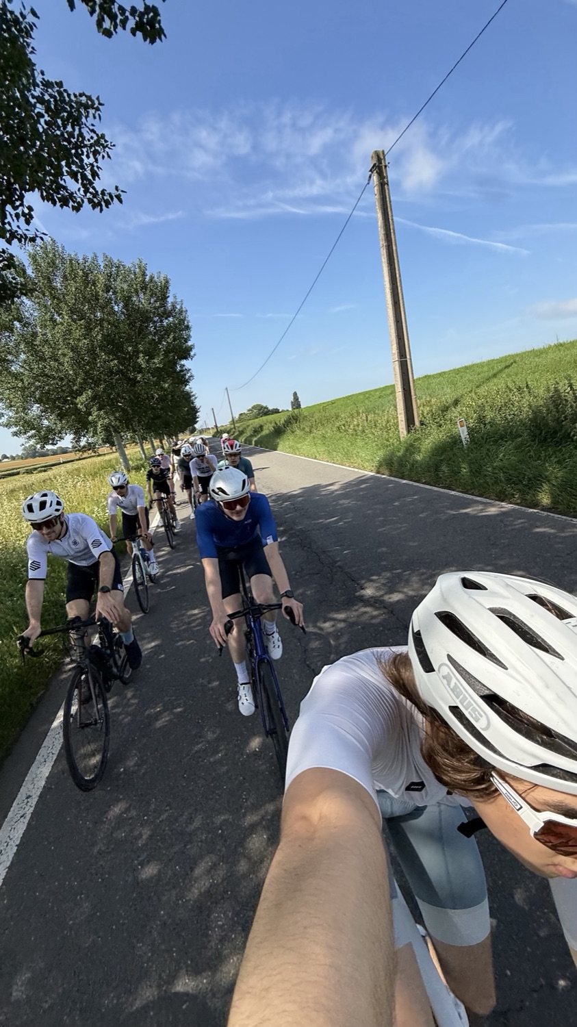 A selfie with the group riding behind, tree-lined road